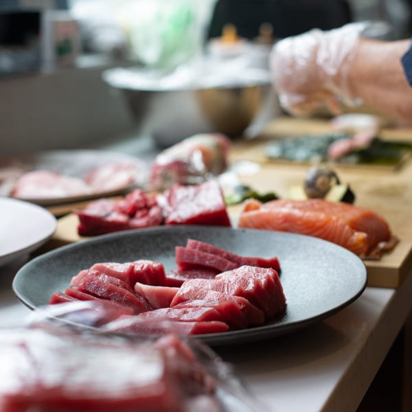 Plates of fresh-cut tuna and salmon sashimi, ready for preparation at Pisces sushi restaurant.
