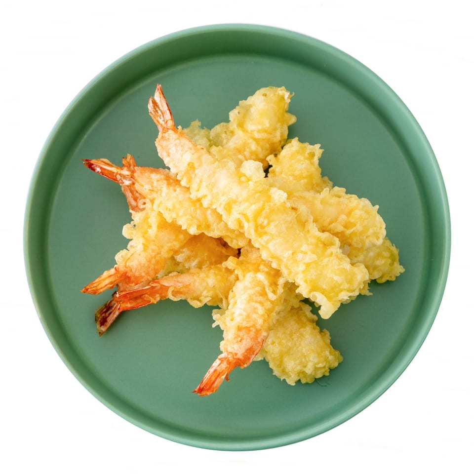 Crispy golden tempura shrimp, a Pisces sushi specialty, arranged on a round green plate.