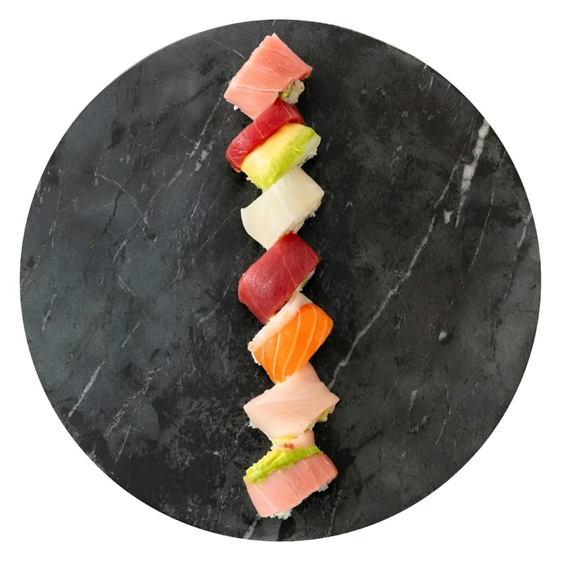 Assorted sushi pieces, including tuna, salmon, and avocado, arranged on a dark marble plate.