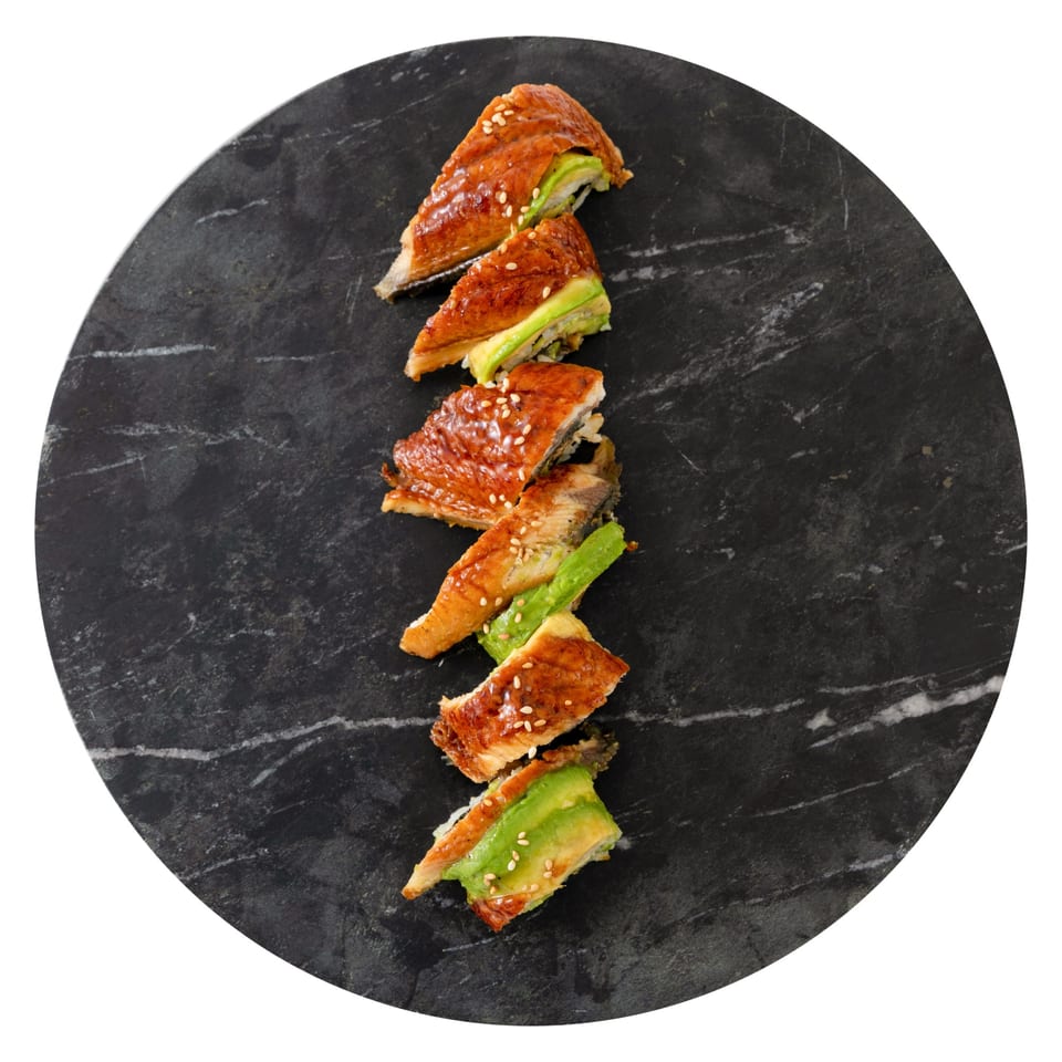 Six pieces of Pisces sushi with eel and avocado, garnished with sesame seeds, on a dark marble plate.