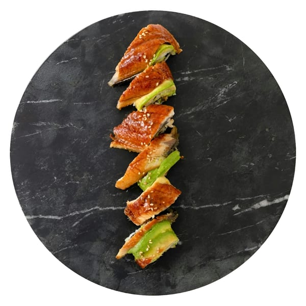 Six pieces of eel and avocado sushi with sesame seeds, arranged on a dark marble plate.