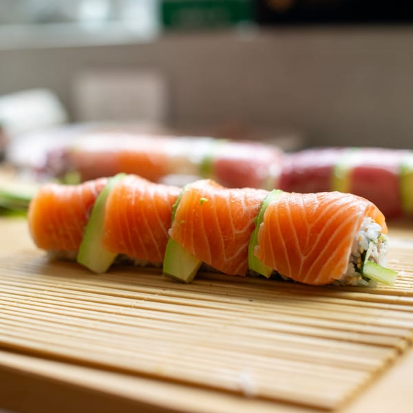 Freshly prepared Pisces sushi rolls with salmon and avocado on a bamboo mat.